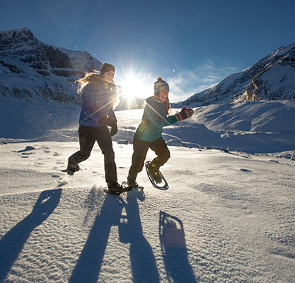 Two women have fun snowshoeing in the mountains.