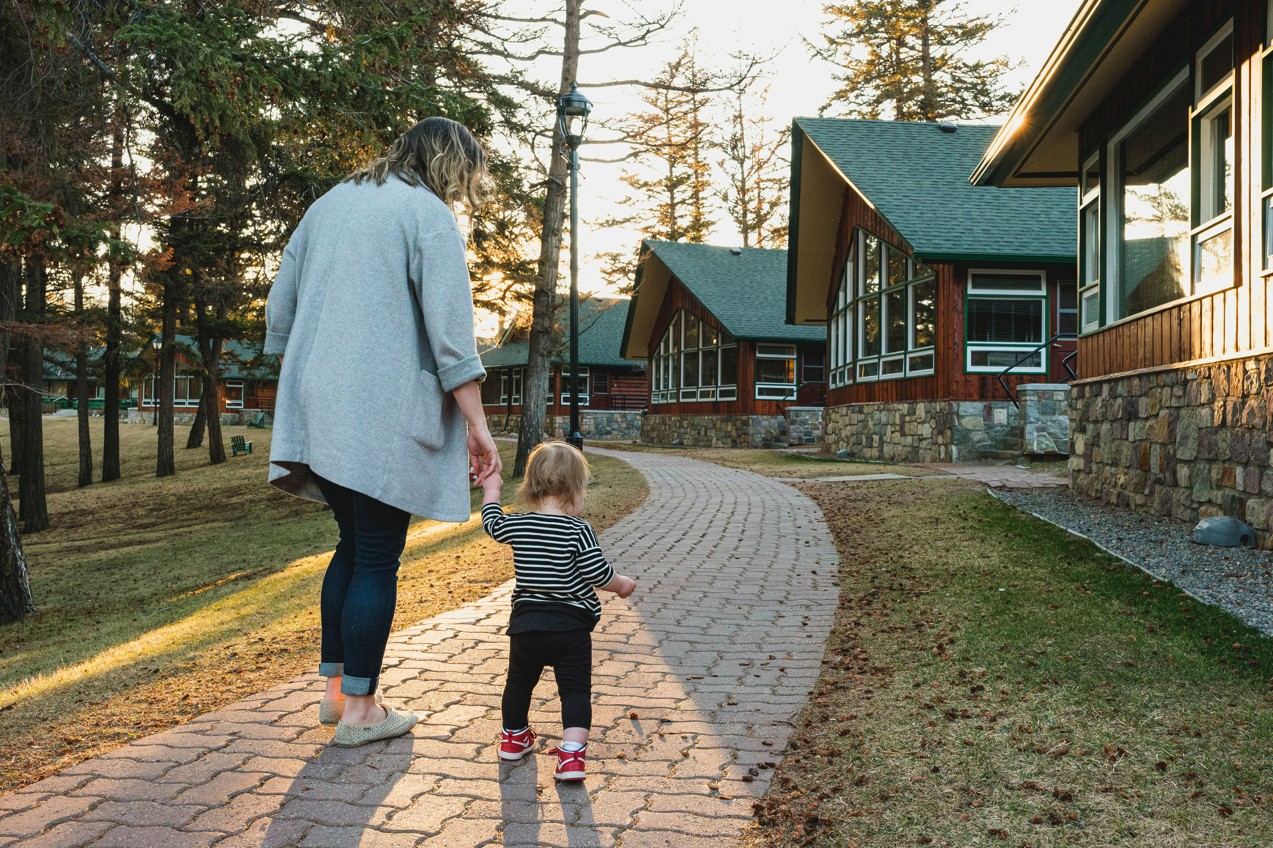 A mother and her toddler walking along a path by the cabins at Jasper Park Lodge in the spring.