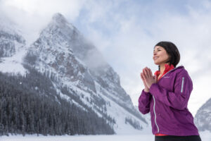 A woman on the shores of frozen Lake Louise. Wellness at the Fairmont Chateau Lake Louise