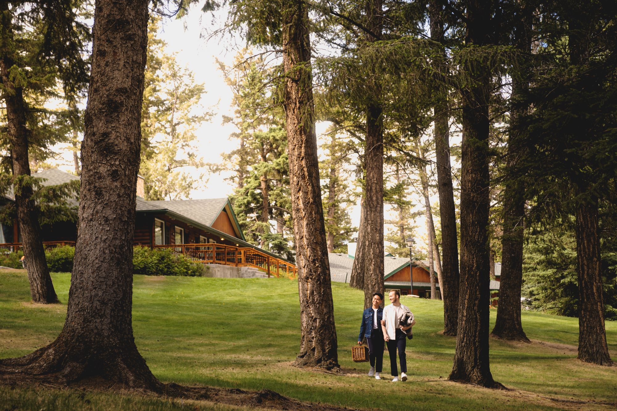 A couple walking through the forest for a picnic at Fairmont Jasper Park Lodge