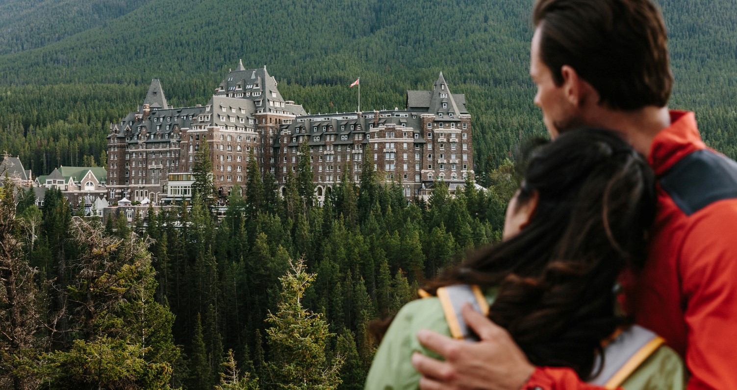 A Couple viewing Fairmont Banff Springs Hotel from Surprise Corner lookout in Banff