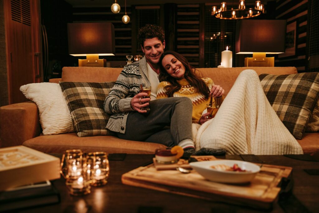 A couple cozied up on the couch with a blanket and candles in Ridgeline Cabin, Fairmont Jasper Park Lodge, part of Canada's top ski destinations