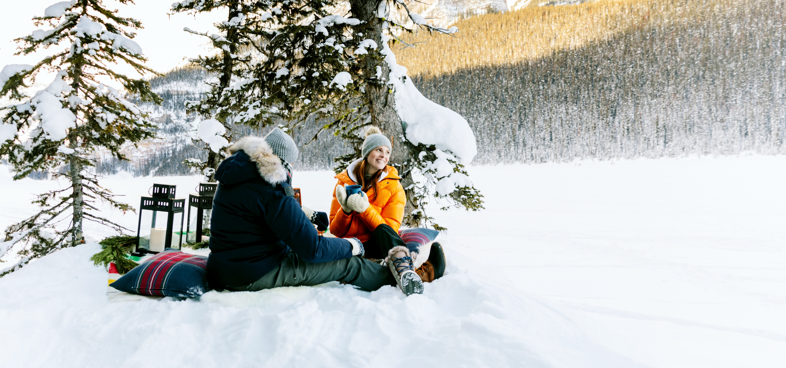A couple sitting in a snowbank in winter at Lake Louise