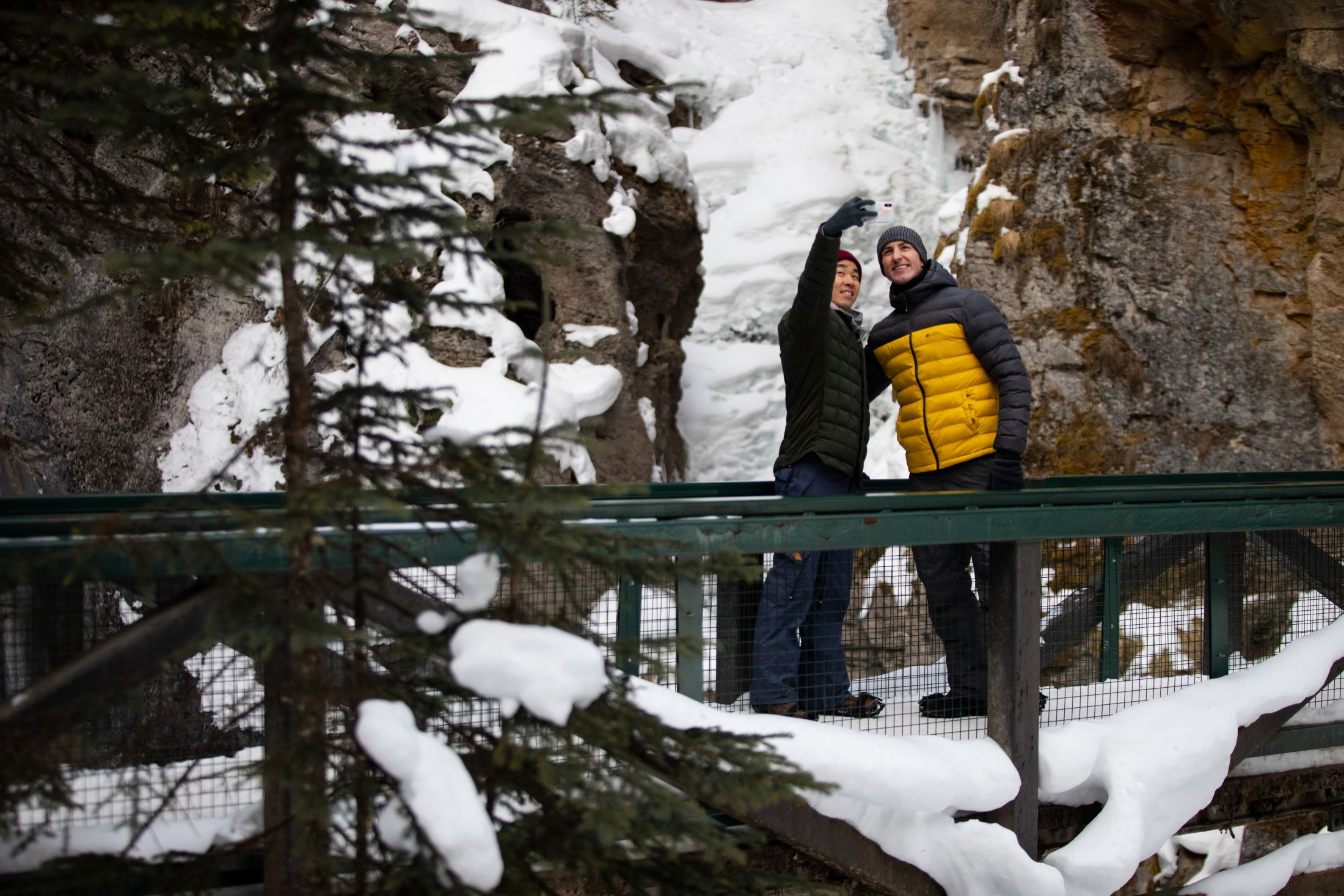 A couple taking a frozen waterfall selfie at Johnston Canyon. Photo by Devaan Ingraham