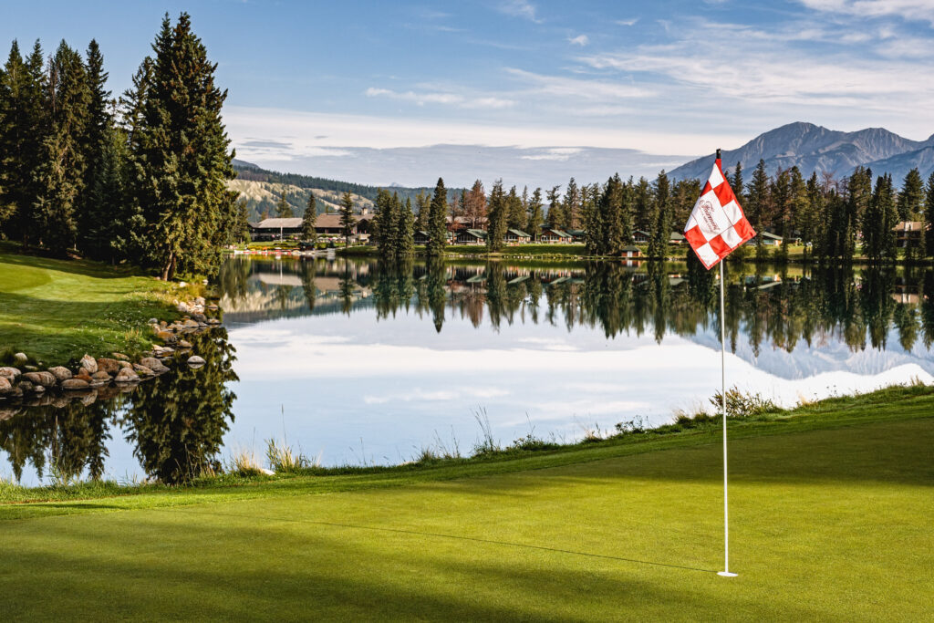 View of the 16th hole on Fairmont Jasper Park Lodge Golf Club showcasing the lodge and the mountains