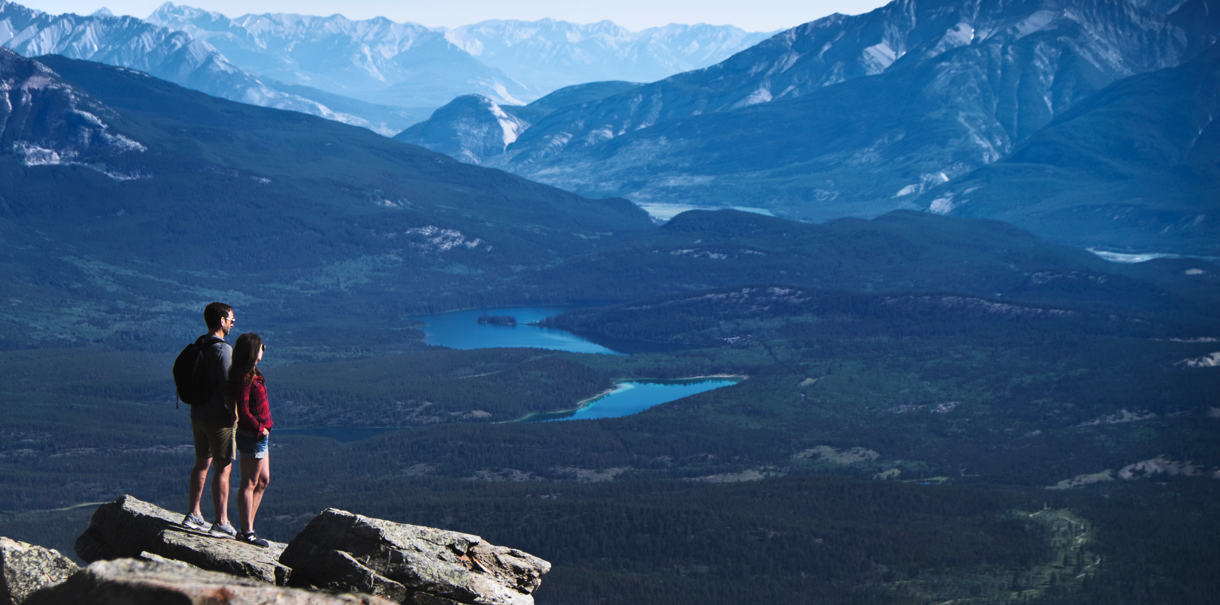 Couple stand on the top of the mountain overlooking Jasper National Park