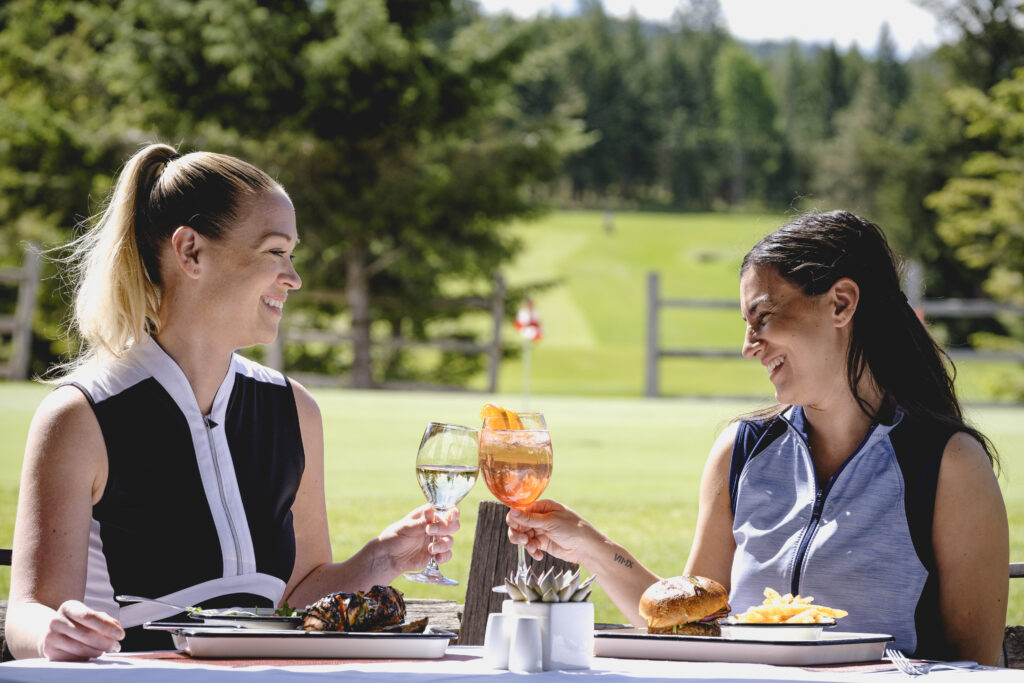 Two women with drinks apres golfing in Jasper at the Fairmont. 